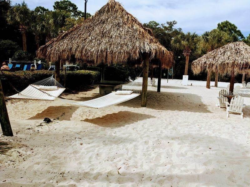 A sandy beach area features two thatched-roof tiki huts and two white rope hammocks — 510 RUM RUN UNIT 510, DAVENPORT, FL