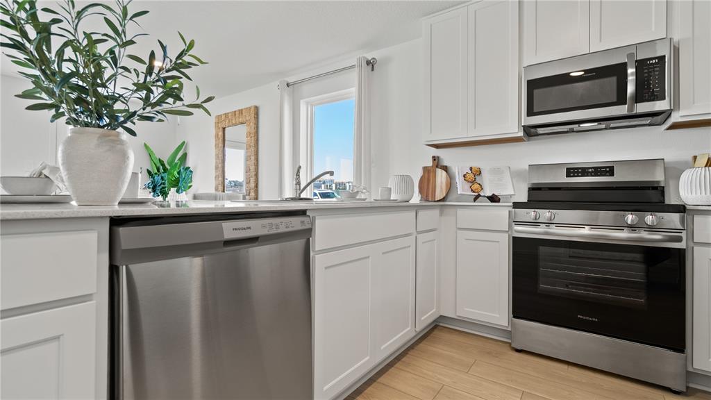 A kitchen features white cabinets, stainless steel appliances, and a window above the sink — 1554 PLANK PLACE, DAVENPORT, FL