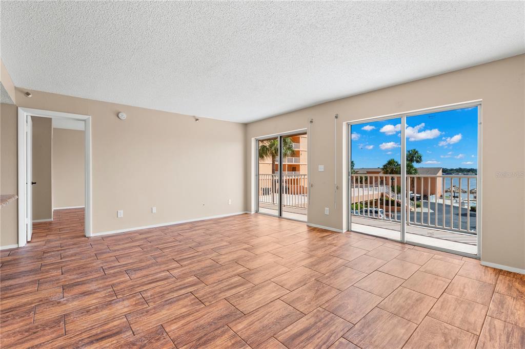 A balcony with outdoor furniture overlooks a parking lot, a tall apartment building, and water — 7432 SUNSHINE SKYWAY LANE S UNIT 302, ST PETERSBURG, FL