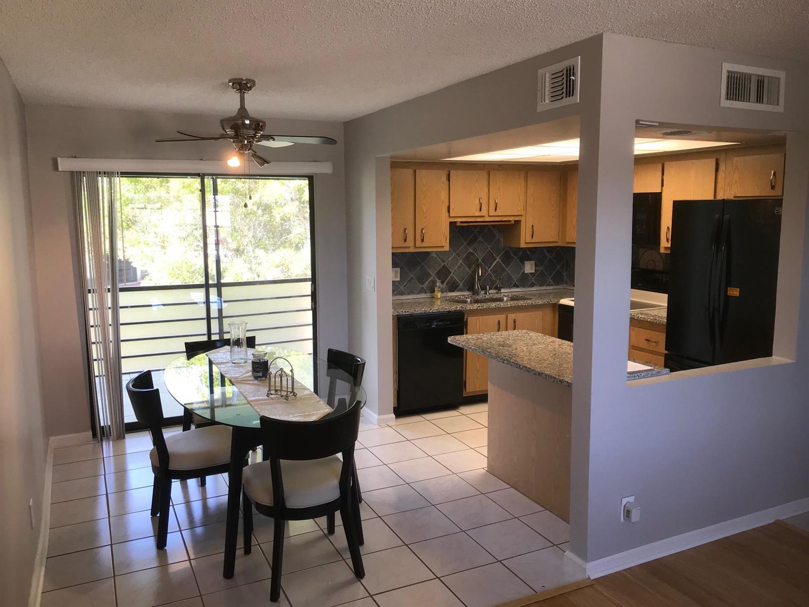 A dining area with a glass table sits adjacent to a kitchen with oak cabinets — 4147 Oak Terrace Drive, FL 33463, FL