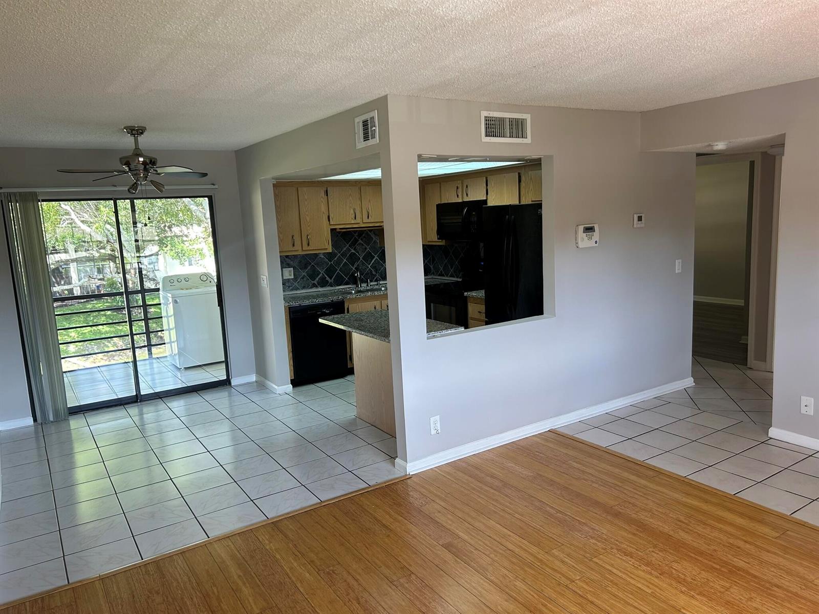 An open-concept living area features wood flooring, a tiled kitchen, and a sliding glass door — 4147 Oak Terrace Drive, FL 33463, FL