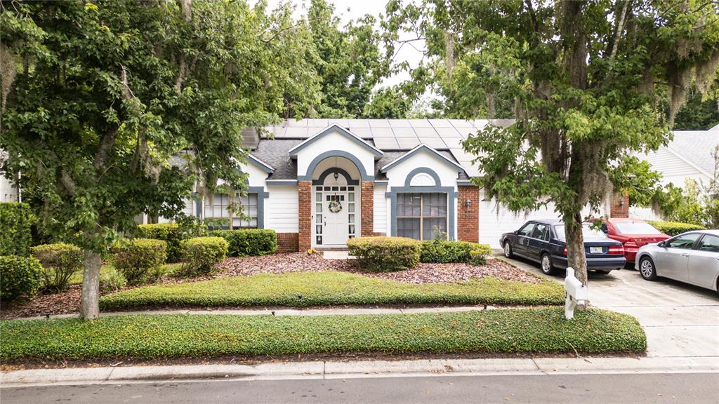 A single-story house with a brick-accented entryway, solar panels on the roof, and a driveway — 1022 SILCOX BRANCH CIRCLE, OVIEDO, FL