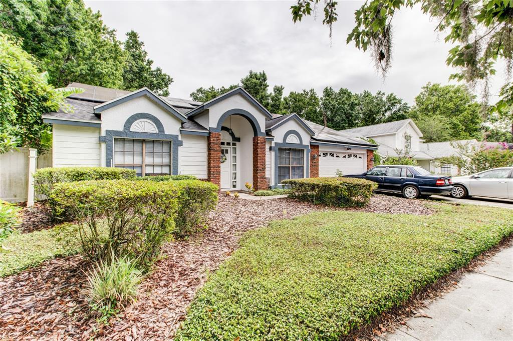 A single-story house with a brick-accented entryway, light siding, and a landscaped front yard — 1022 SILCOX BRANCH CIRCLE, OVIEDO, FL