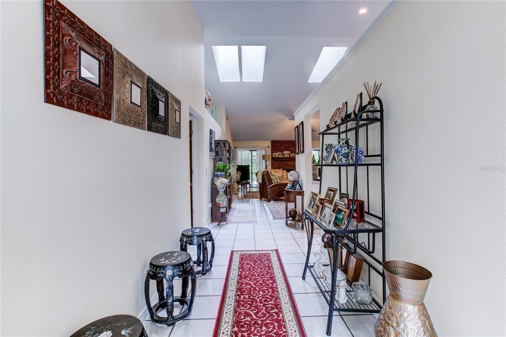 A tiled hallway features a red runner rug, wall-mounted mirrors, and a black metal shelf — 1022 SILCOX BRANCH CIRCLE, OVIEDO, FL