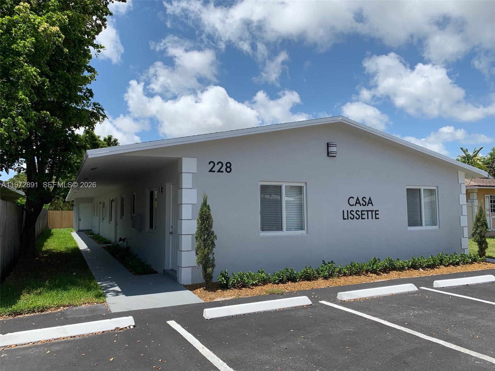 A single-story gray building with a parking lot and a covered walkway in front — FORT LAUDERDALE, FL