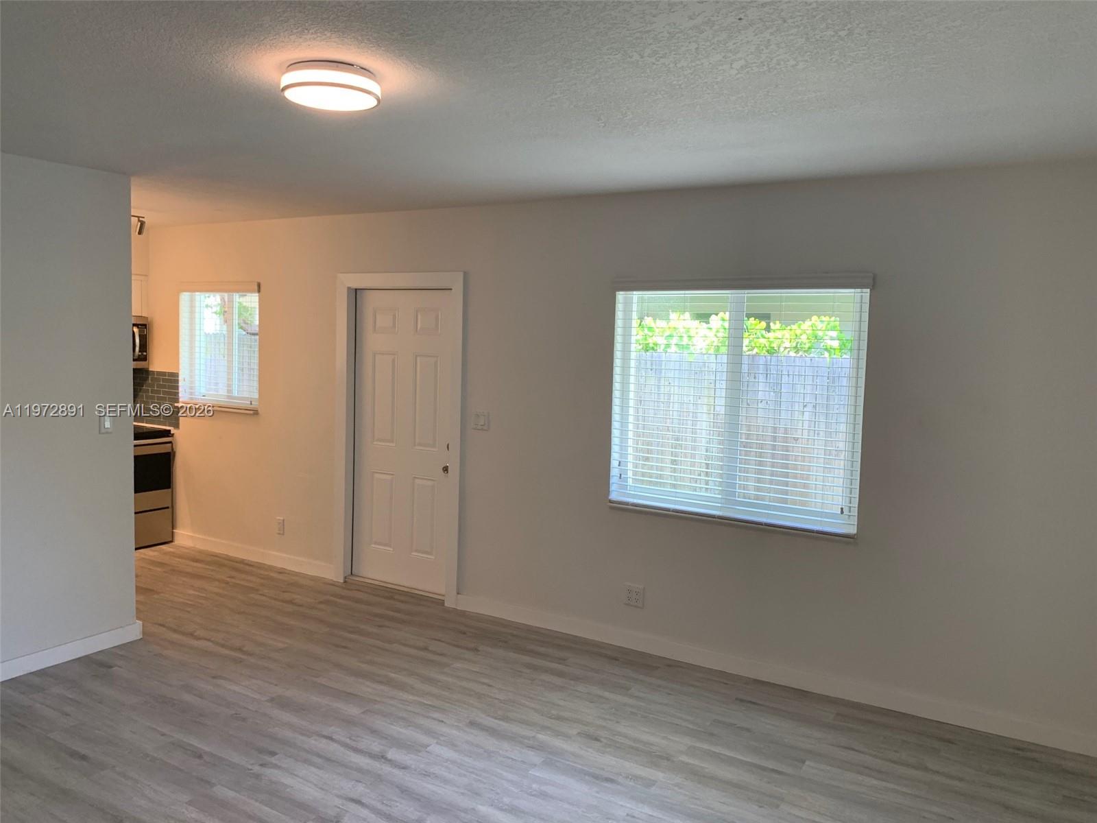 A room with light-colored flooring, a white door, and a window with blinds — FORT LAUDERDALE, FL