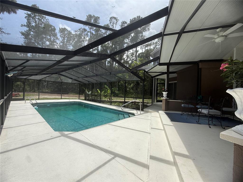 A screened-in pool enclosure features a rectangular swimming pool and a covered concrete patio area — 1143 SHELL HARBOR ROAD, PIERSON, FL