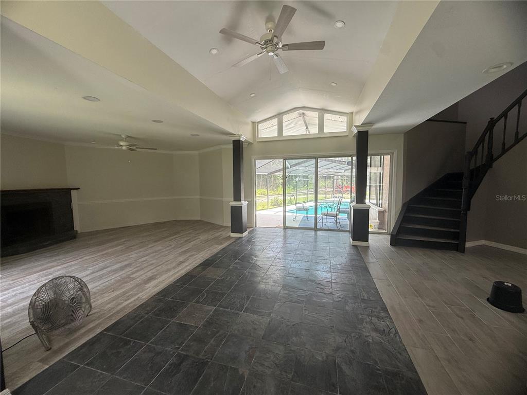 A living room with vaulted ceilings, dark tile flooring, a fireplace, and a staircase — 1143 SHELL HARBOR ROAD, PIERSON, FL