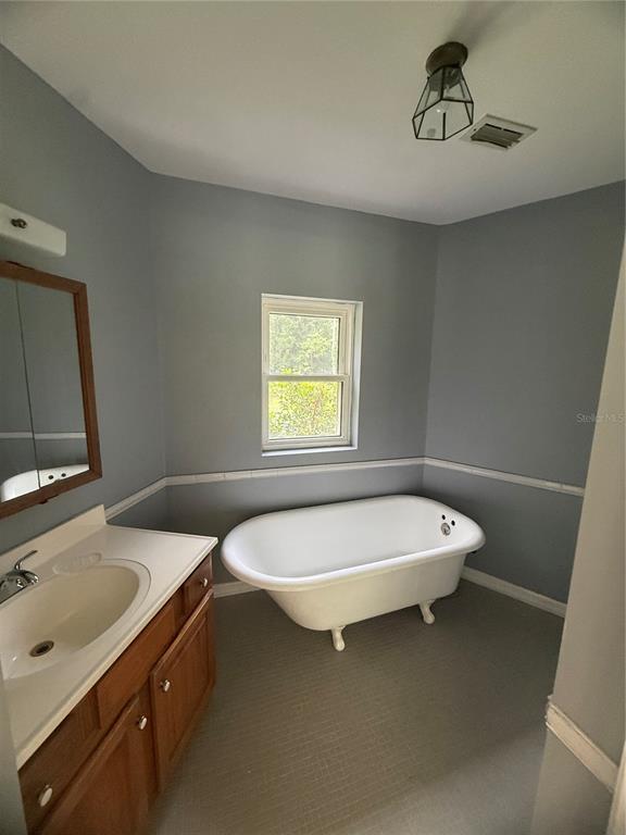 A bathroom features a clawfoot tub, a wooden vanity with a sink, and gray walls — 1143 SHELL HARBOR ROAD, PIERSON, FL