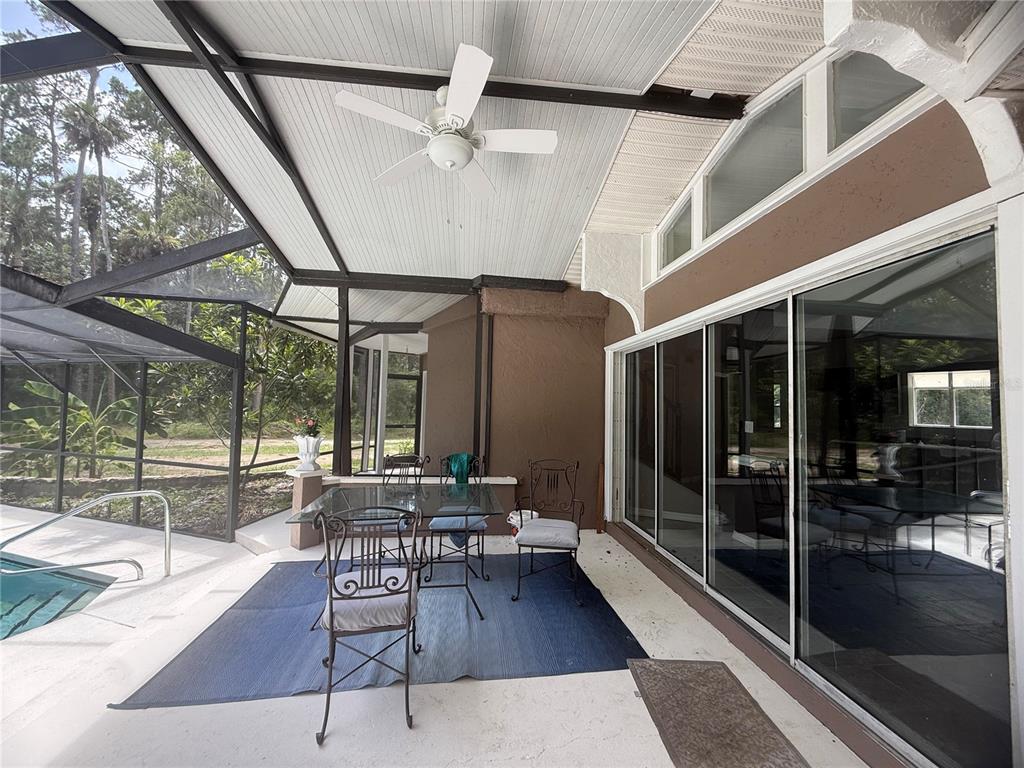 A covered patio with a ceiling fan, dining set, and sliding glass doors beside a pool — 1143 SHELL HARBOR ROAD, PIERSON, FL