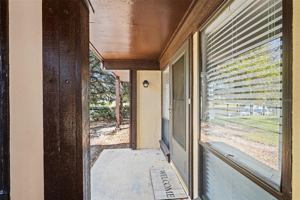 A covered entryway features a concrete porch, a brown front door, and a welcome mat — 42 CLUB HOUSE DRIVE UNIT 101, PALM COAST, FL