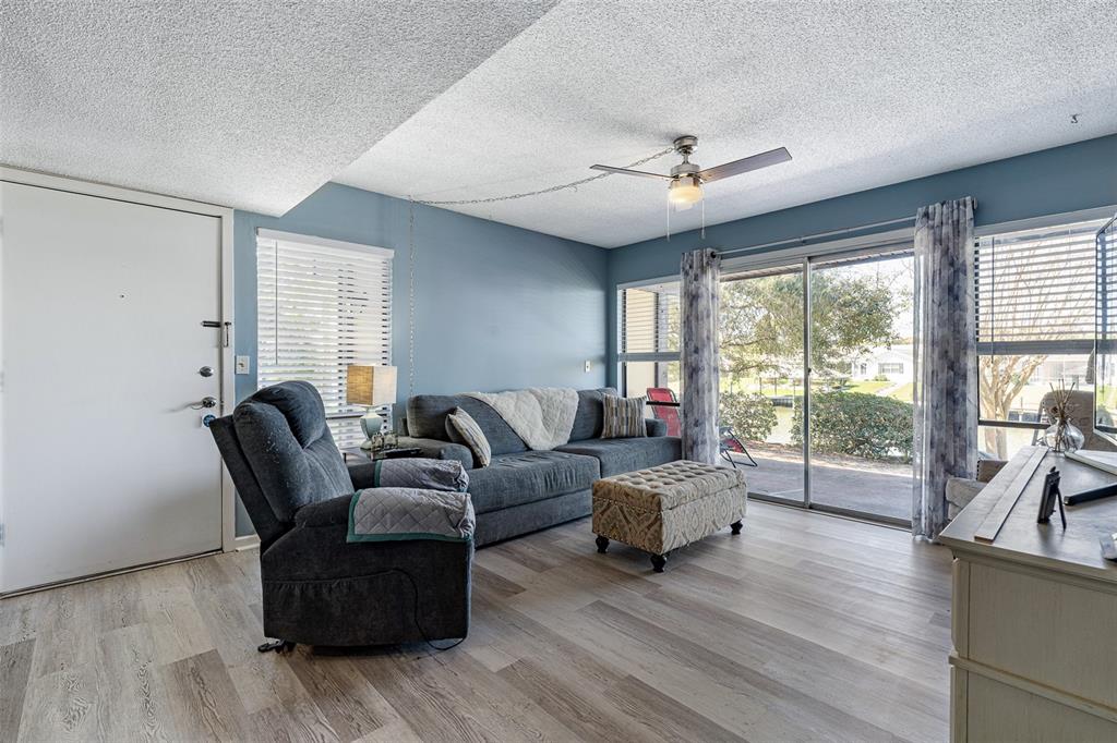 A living room features a grey sofa, recliner, ottoman, and sliding glass doors to a patio — 42 CLUB HOUSE DRIVE UNIT 101, PALM COAST, FL