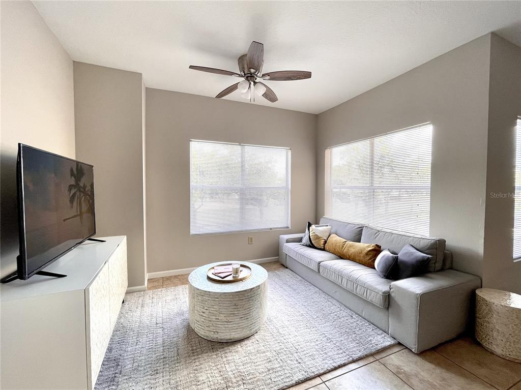 A living room features a gray sofa, a round coffee table, and a television console — 10764 70TH AVENUE UNIT 5205, SEMINOLE, FL