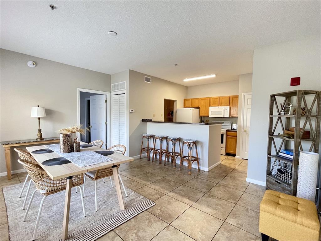 A dining area with a table and chairs sits adjacent to a kitchen with bar seating — 10764 70TH AVENUE UNIT 5205, SEMINOLE, FL