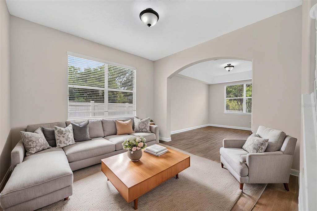 A living room features a sectional sofa, a wooden coffee table, and an arched entryway — 166 W 11TH STREET, CHULUOTA, FL