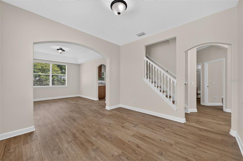 An interior view of a living area with wood-look flooring, an arched entryway, and stairs — 166 W 11TH STREET, CHULUOTA, FL