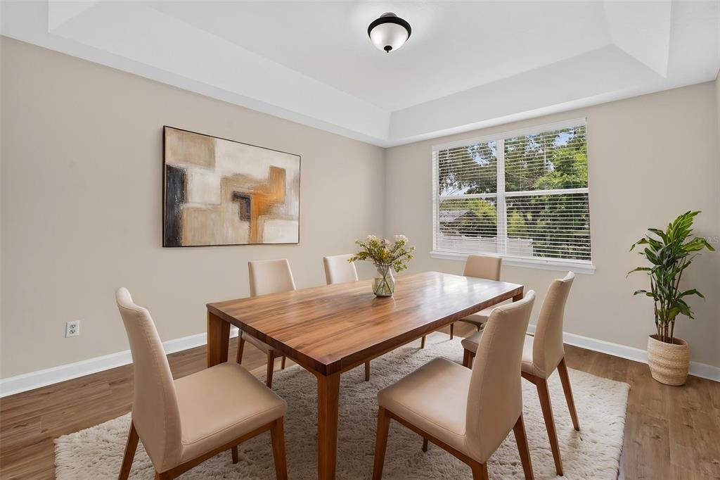 A dining room features a wooden table, six chairs, a rug, and abstract wall art — 166 W 11TH STREET, CHULUOTA, FL