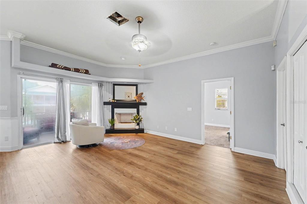 A living room features light gray walls, wood-look flooring, a corner fireplace, and a ceiling fan — 7533 HATTERAS DR, HUDSON, FL