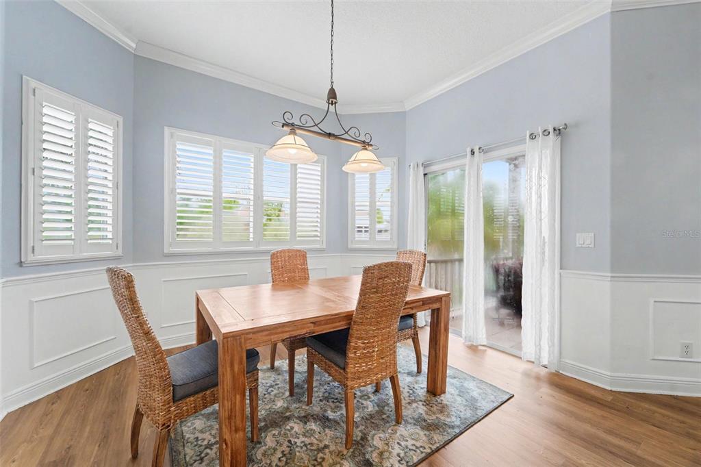 A dining room features a wooden table, wicker chairs, a chandelier, and white wainscoting — 7533 HATTERAS DR, HUDSON, FL