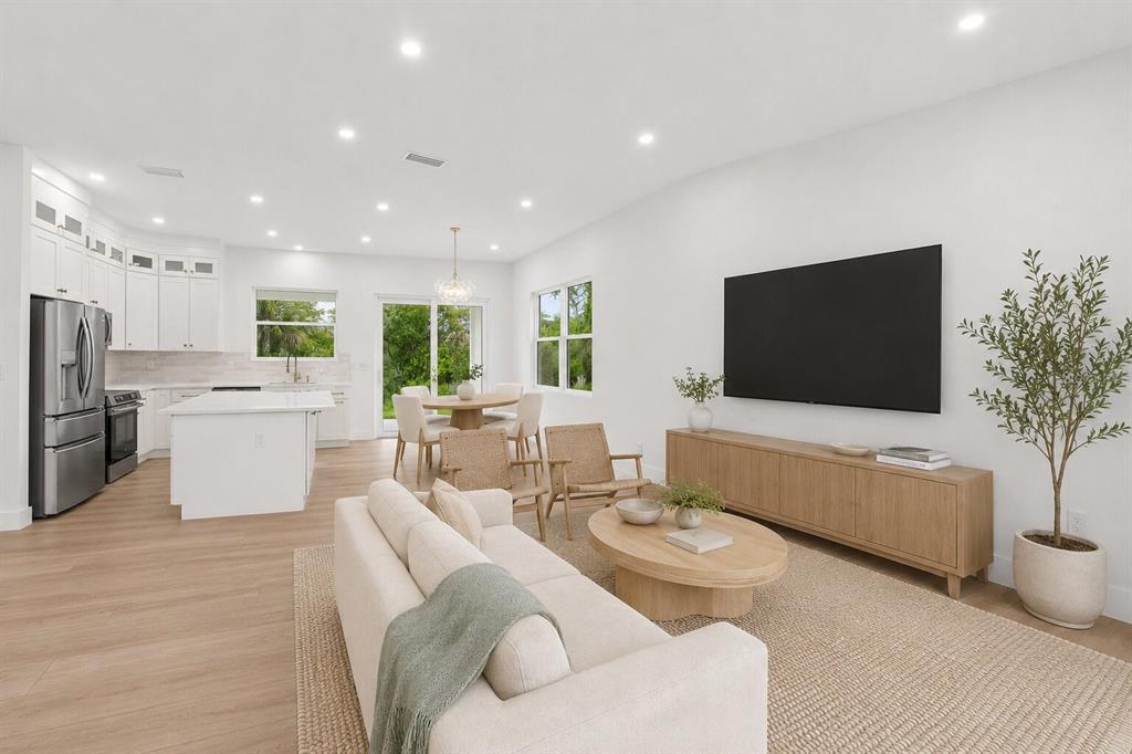 A bright, open-concept living room and kitchen featuring light wood floors and neutral furniture — 2277 SIMONTON AVENUE, NORTH PORT, FL
