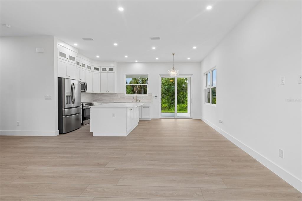 A modern, open-concept kitchen and living area with white cabinets, stainless appliances, and light flooring — 2277 SIMONTON AVENUE, NORTH PORT, FL