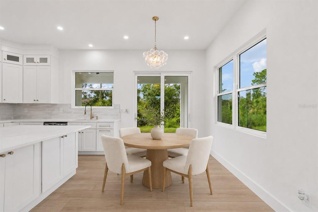 A bright kitchen and dining area with white cabinetry, a round table, and sliding doors — 2277 SIMONTON AVENUE, NORTH PORT, FL