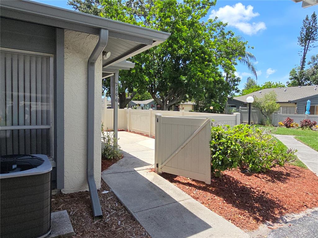 A concrete walkway leads to a gated patio area next to a house exterior — 2606 29TH AVE W UNIT 12, BRADENTON, FL
