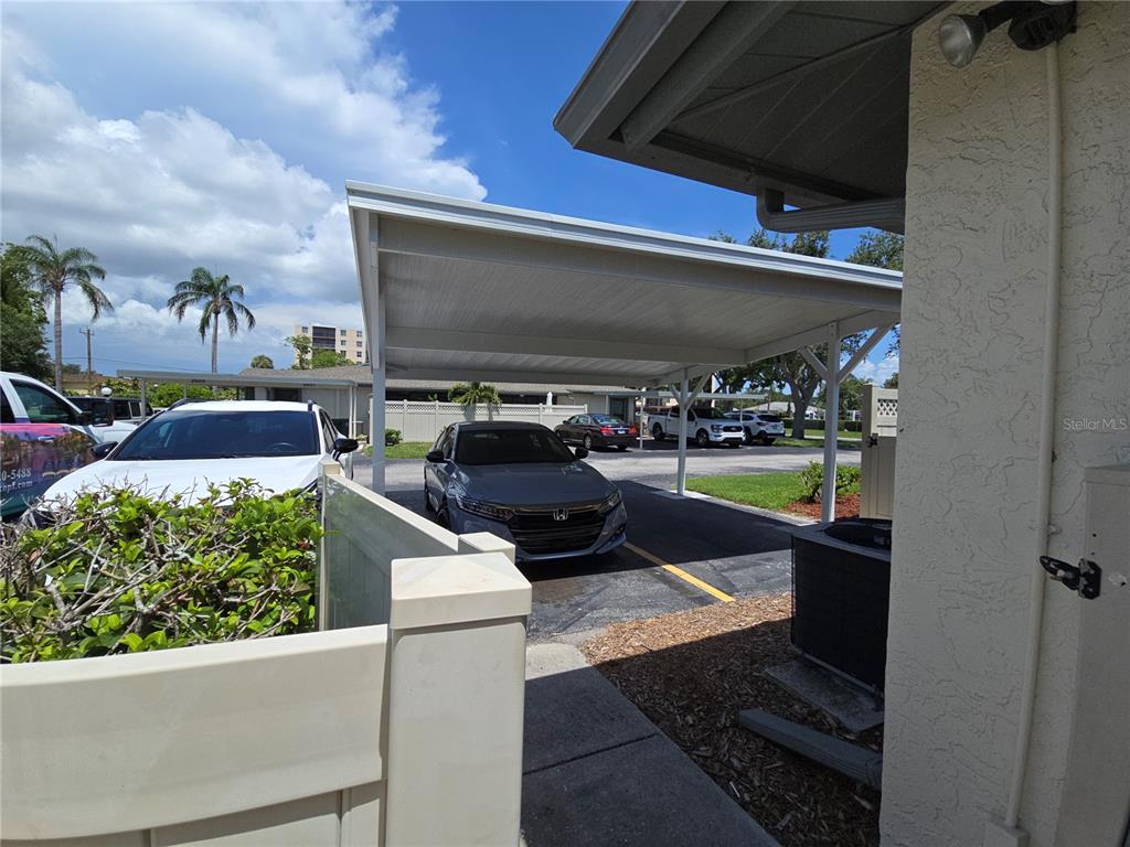 A covered carport shelters a gray sedan parked on an asphalt lot next to a building — 2606 29TH AVE W UNIT 12, BRADENTON, FL