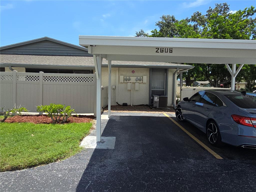 A carport covers a paved driveway in front of a single-story residential building — 2606 29TH AVE W UNIT 12, BRADENTON, FL