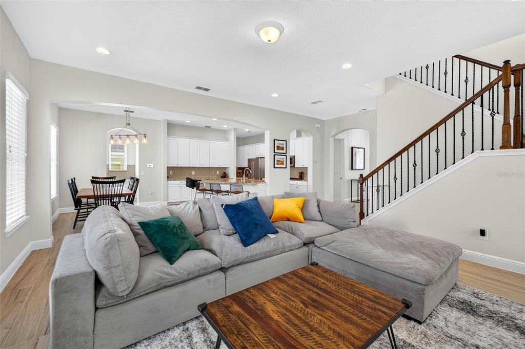 A living room with a large grey sectional sofa, wooden coffee table, and an open kitchen — 5954 CALDERA RIDGE DRIVE, LITHIA, FL