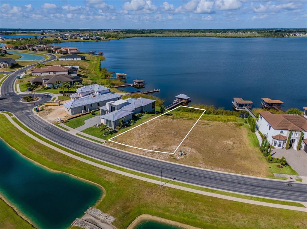 An aerial view shows a vacant waterfront residential lot outlined in white next to houses — 707 WATERFERN TRAIL DRIVE, AUBURNDALE, FL