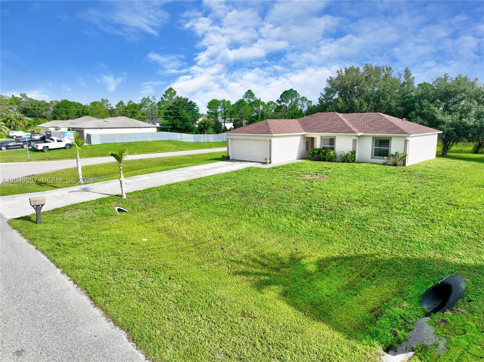 A single-story house with a beige exterior, brown roof, and a concrete driveway — 446 Windermere Dr., Lehigh Acres FL 33972, LEHIGH ACRES, FL