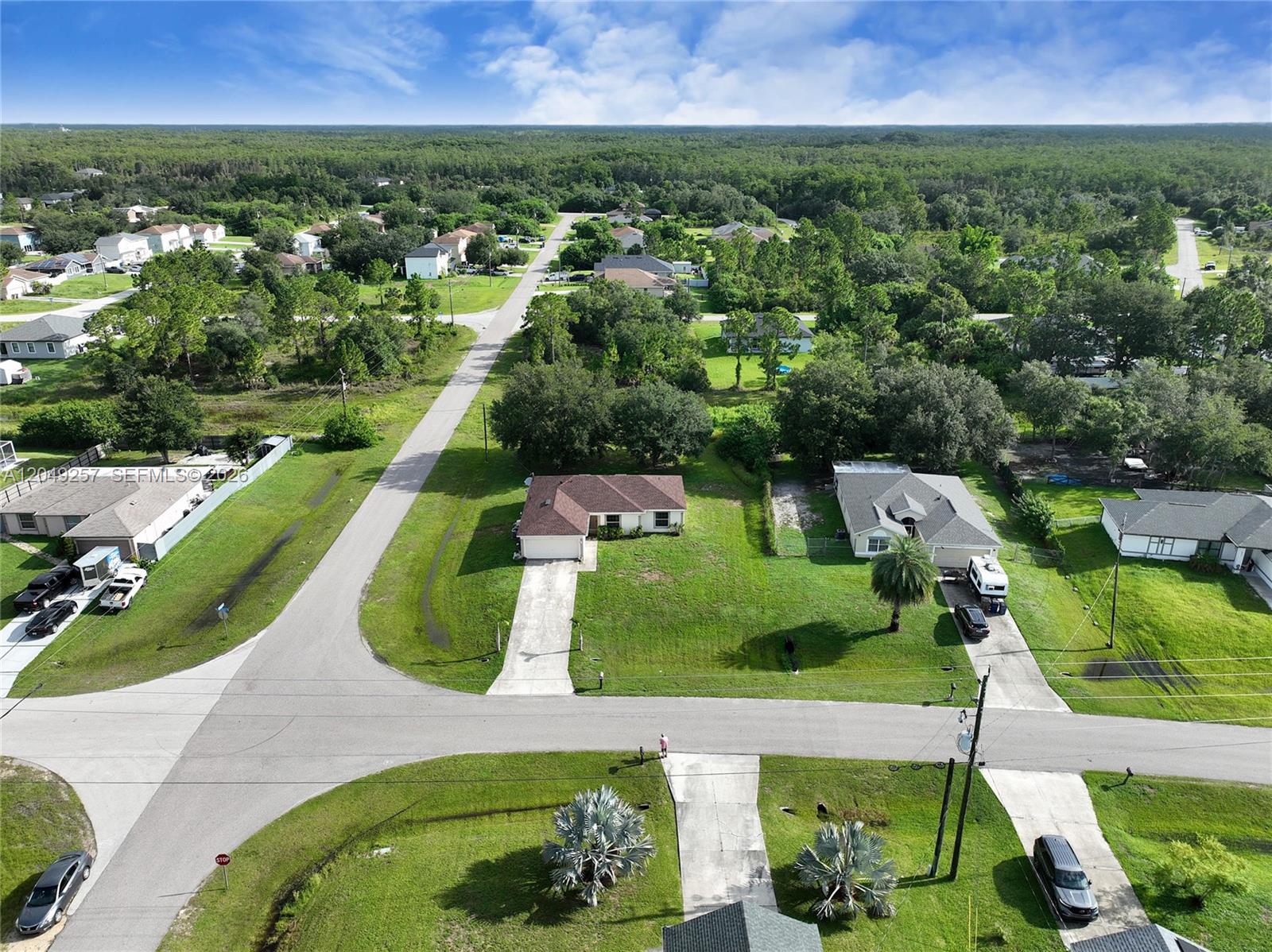 An aerial view shows a suburban street with houses, driveways, and surrounding trees — 446 Windermere Dr., Lehigh Acres FL 33972, LEHIGH ACRES, FL