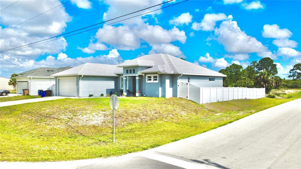 A light blue single-story house with a gray roof and a white vinyl privacy fence — 3900 21ST STREET SW, LEHIGH ACRES, FL
