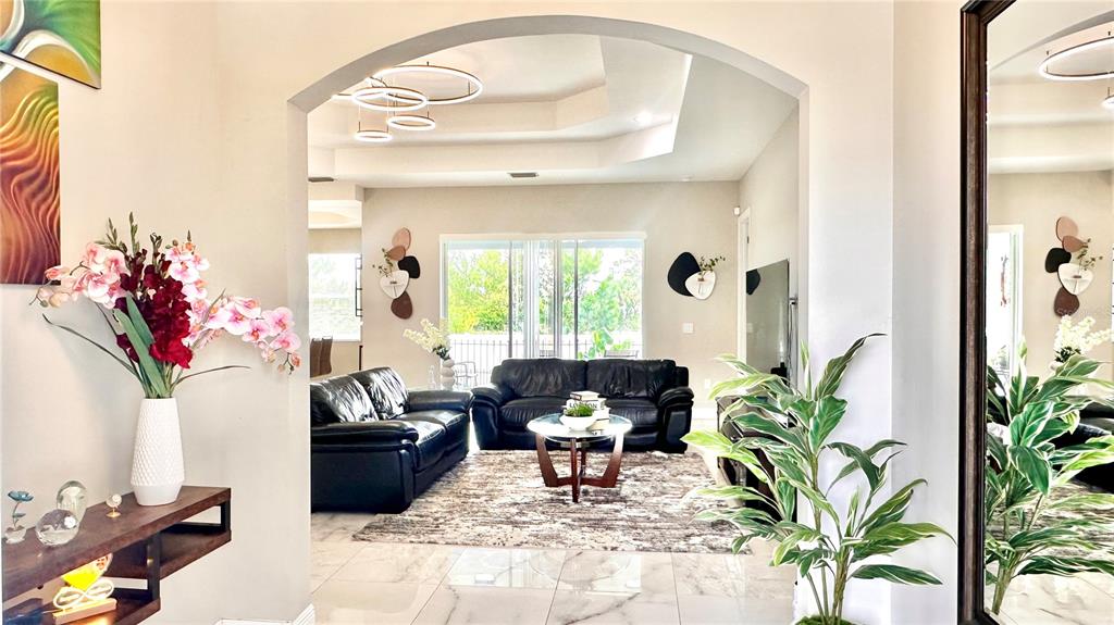 A living room with black leather sofas, a coffee table, and a tray ceiling — 3900 21ST STREET SW, LEHIGH ACRES, FL