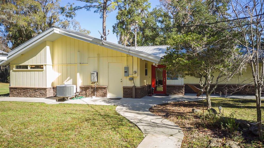 A yellow house with a stone base, metal roof, and a red front door — 11371 N HONEY JORDEN POINT, INGLIS, FL