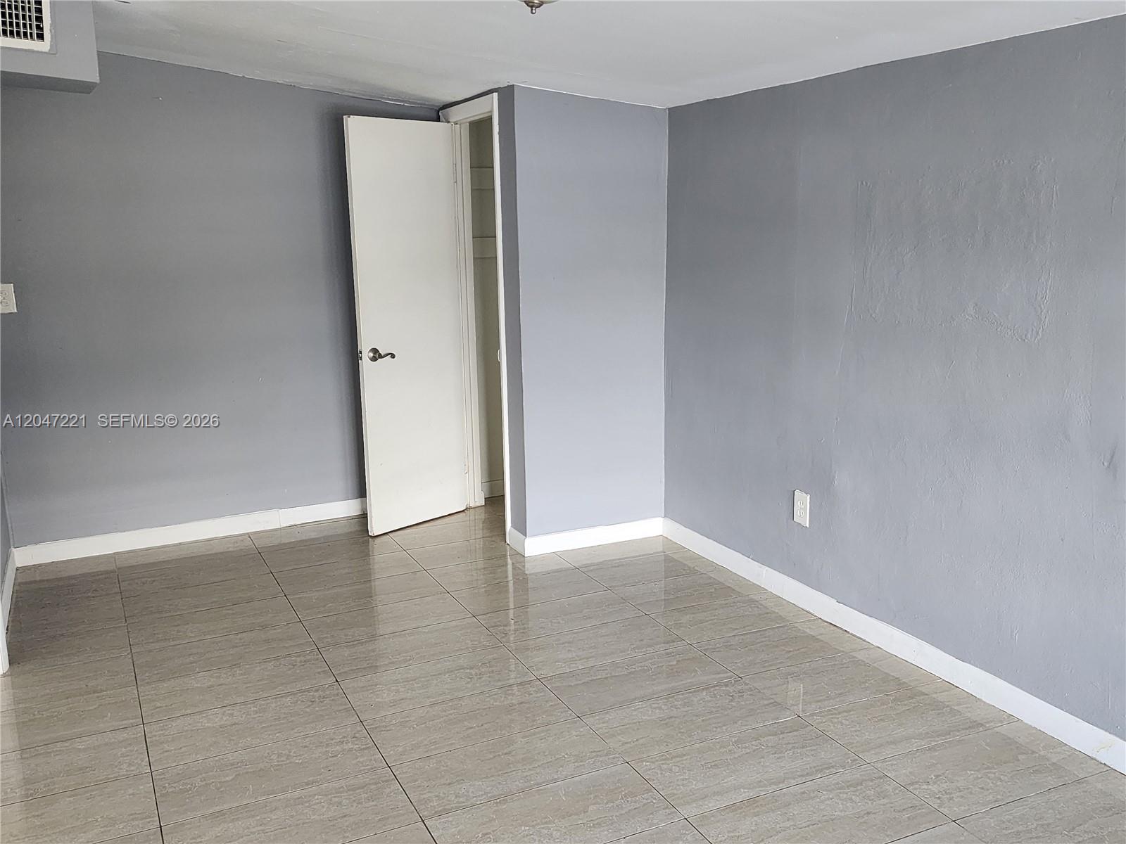 An empty room features gray walls, white trim, and light-colored tile flooring — 4100 SW 36th St # 0, West Park FL 33023, WEST PARK, FL