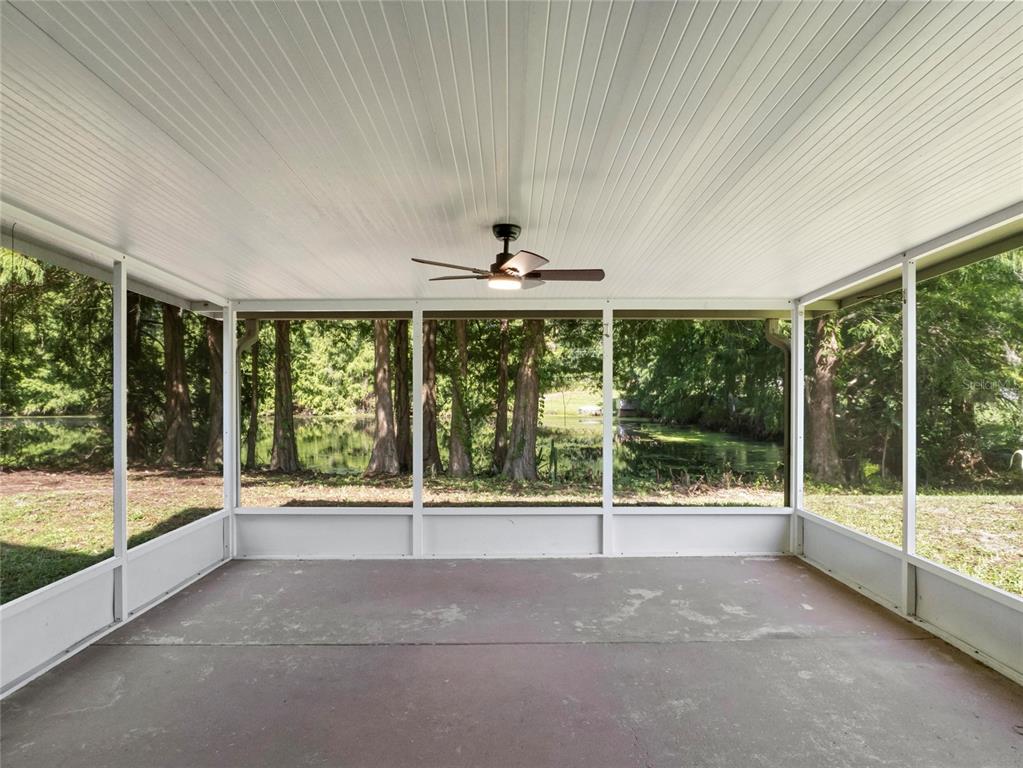 A screened-in porch with a concrete floor, a ceiling fan, and a view of trees — 416 SAND PEBBLE COVE, LONGWOOD, FL