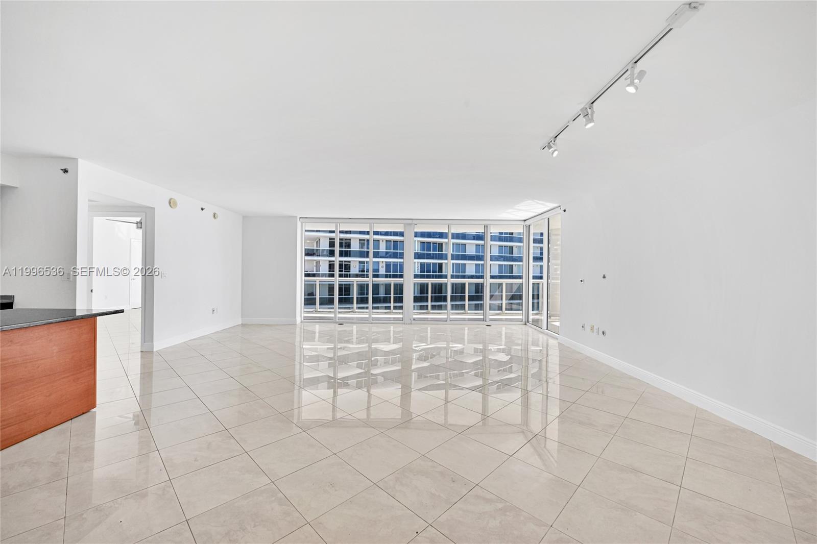 An empty room with large floor-to-ceiling windows, white walls, and light-colored tile flooring — 1850 S Ocean Dr # 3510, Hallandale Beach FL 33009, HALLANDALE BEACH, FL