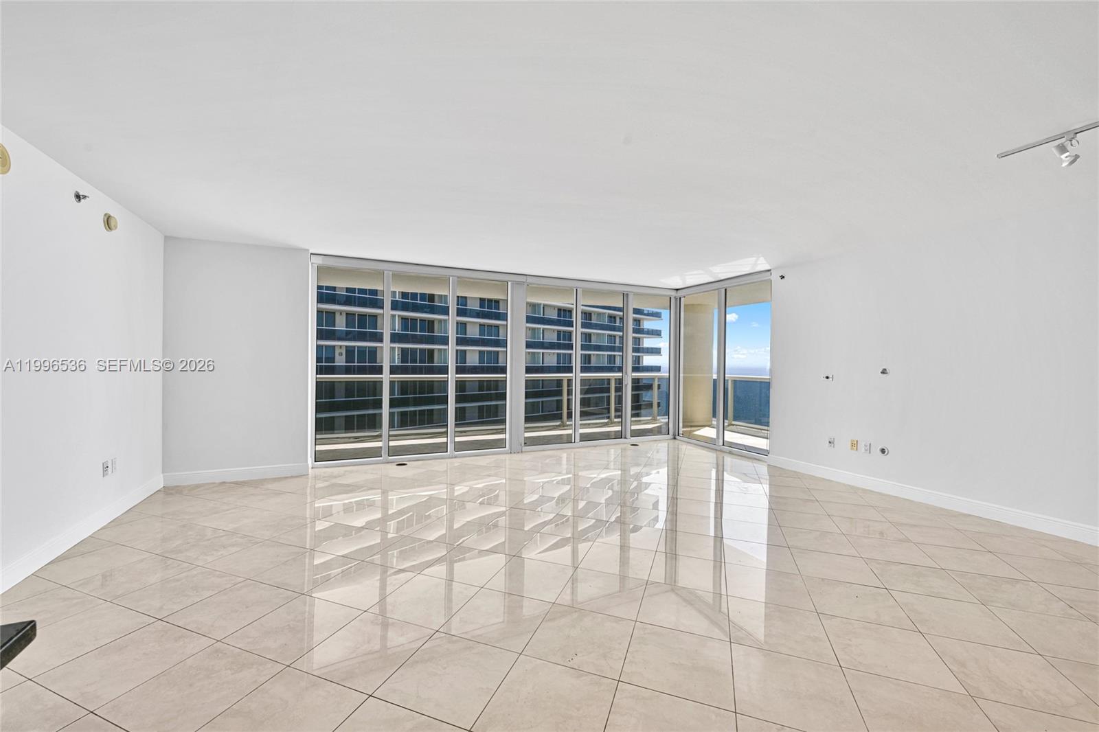 A bright, empty room features large floor-to-ceiling windows, light tile flooring, and white walls — 1850 S Ocean Dr # 3510, Hallandale Beach FL 33009, HALLANDALE BEACH, FL