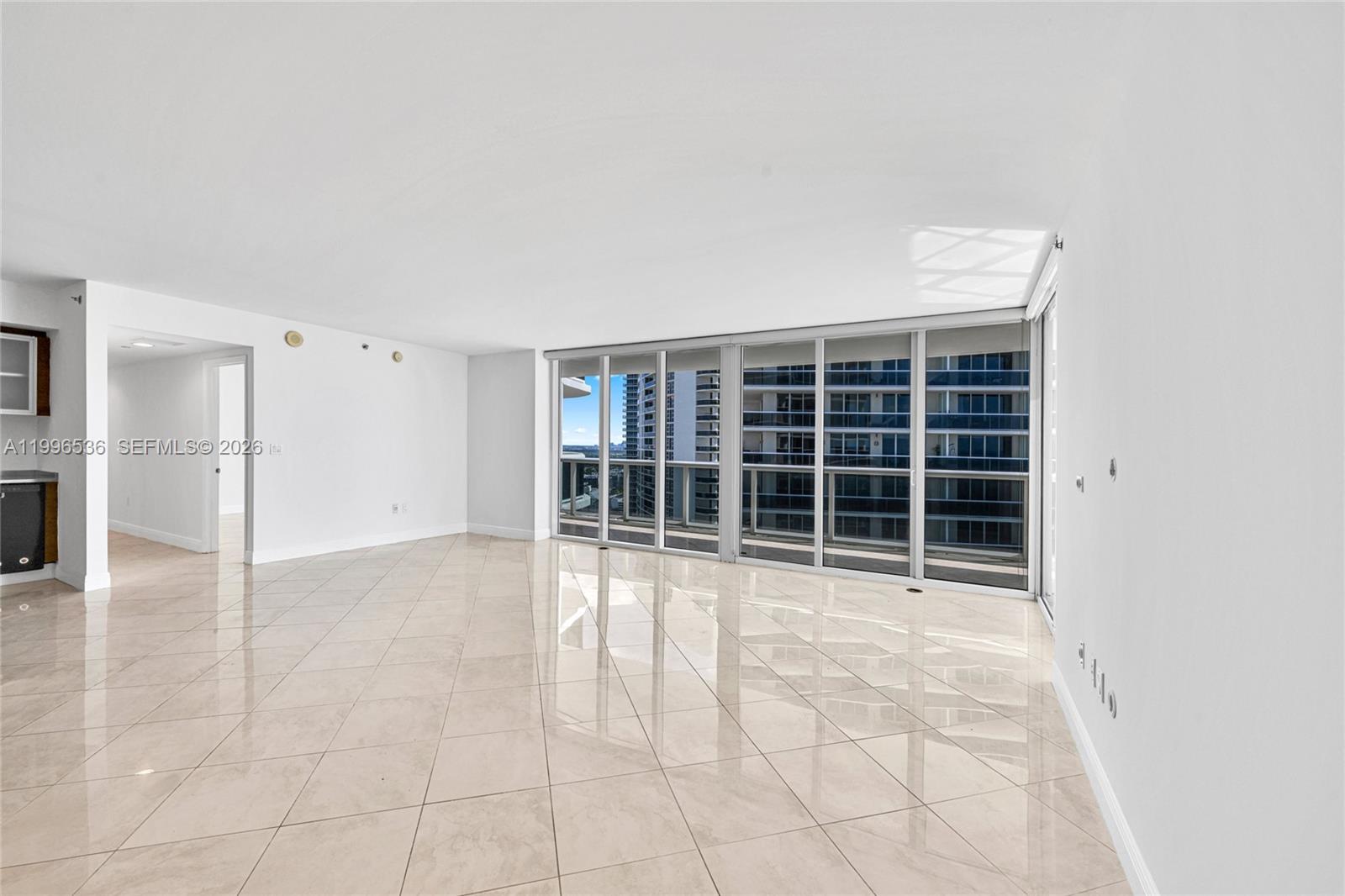 An empty living room with light-colored tile flooring and floor-to-ceiling windows overlooking a city — 1850 S Ocean Dr # 3510, Hallandale Beach FL 33009, HALLANDALE BEACH, FL