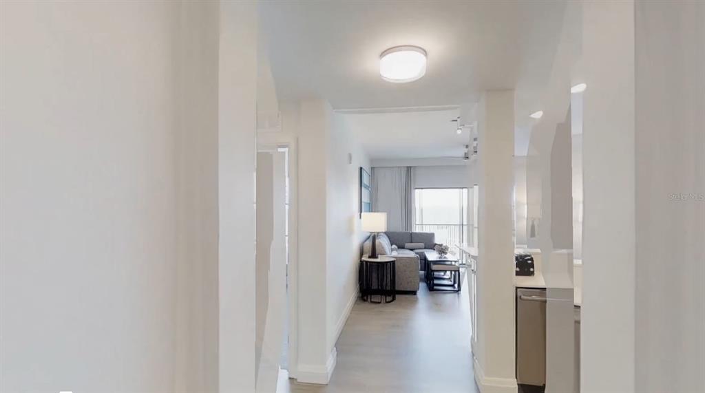 A hallway leads into a living room with light flooring, neutral walls, and a balcony — 14501 GROVE RESORT AVENUE UNIT 2423, WINTER GARDEN, FL