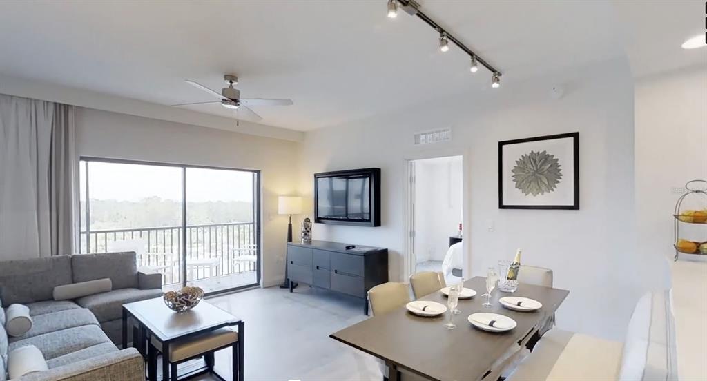 A living and dining area features a gray sofa, a dining table, and a balcony — 14501 GROVE RESORT AVENUE UNIT 2423, WINTER GARDEN, FL