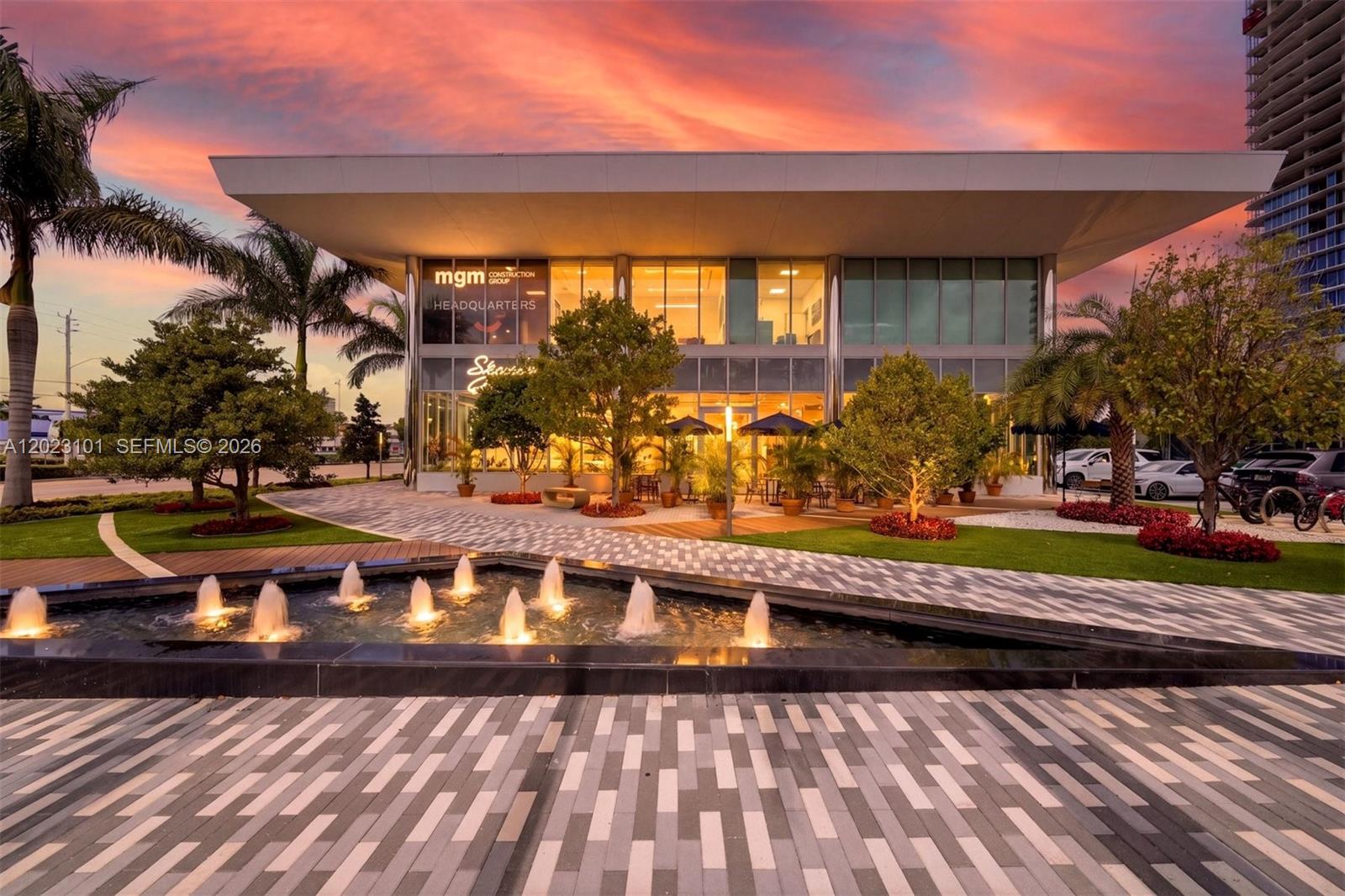 A modern two-story building with a fountain in the foreground under a sunset sky — 1006 E Hallandale Beach Blvd # 103, Hallandale Beach FL 33009, HALLANDALE BEACH, FL