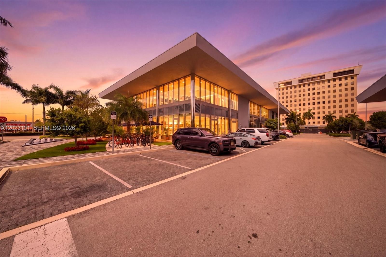 A modern glass-walled commercial building stands in a parking lot at sunset — 1006 E Hallandale Beach Blvd # 103, Hallandale Beach FL 33009, HALLANDALE BEACH, FL