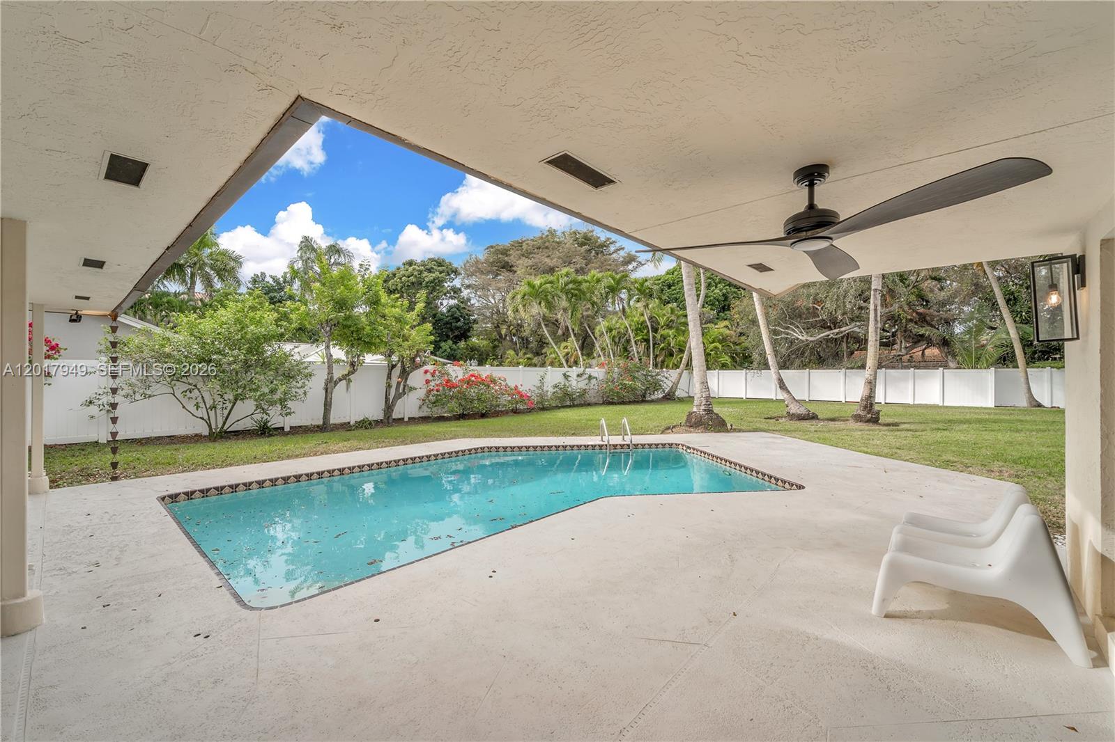 A covered patio overlooks a swimming pool and a fenced backyard with palm trees — 10330 SW 58th Ct, Pinecrest FL 33156, PINECREST, FL