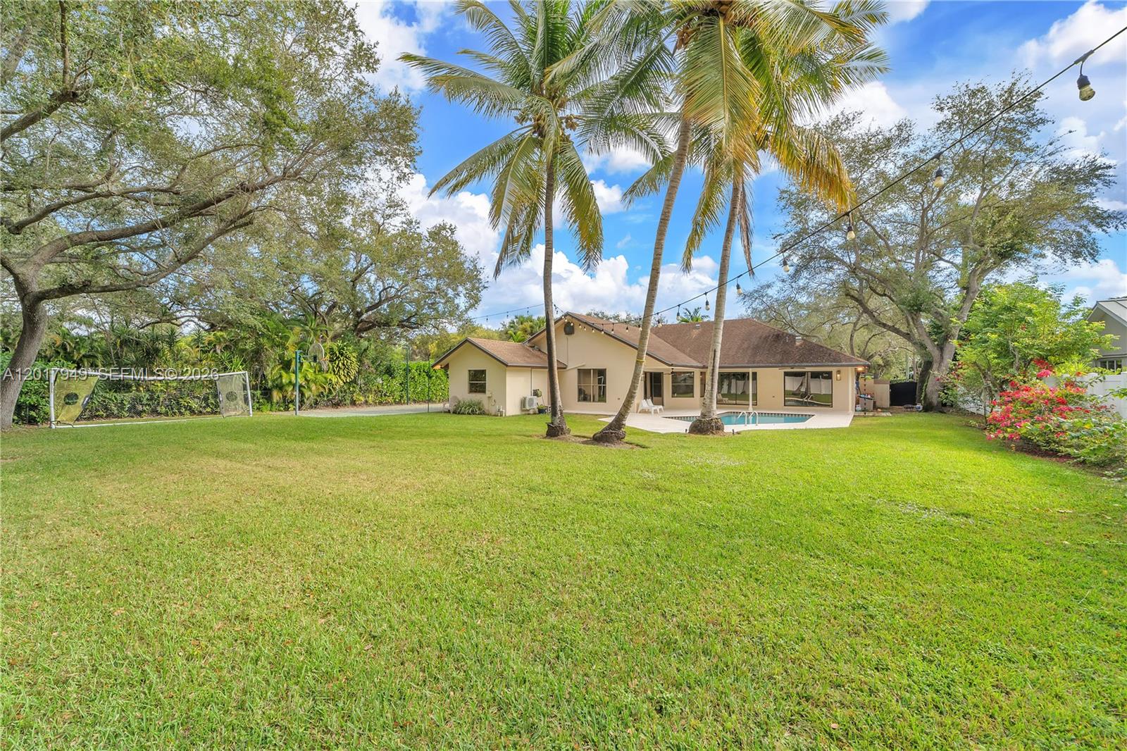 A backyard features a swimming pool, palm trees, a large lawn, and a residential house — 10330 SW 58th Ct, Pinecrest FL 33156, PINECREST, FL