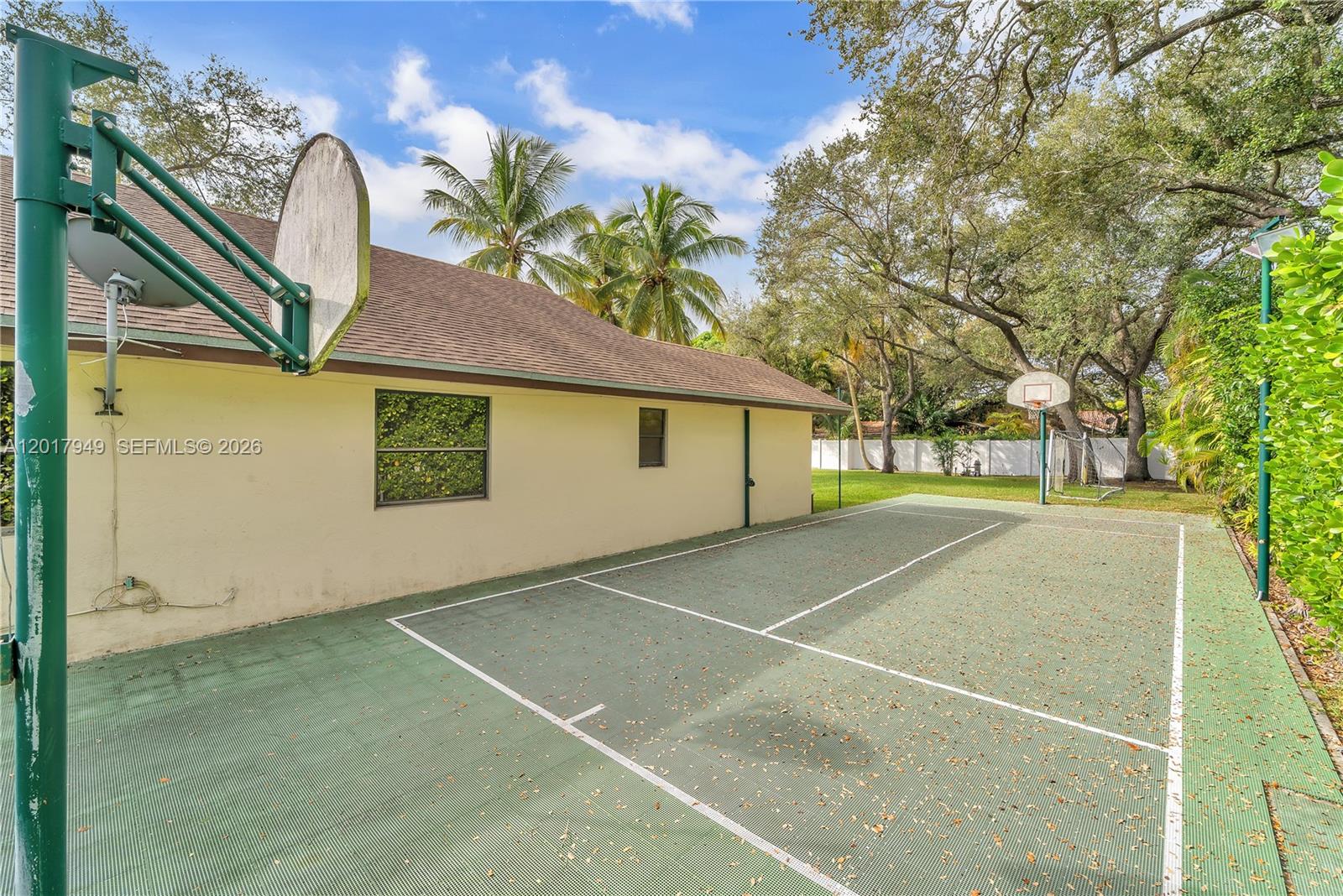 A backyard features a green sports court with two basketball hoops and a house exterior — 10330 SW 58th Ct, Pinecrest FL 33156, PINECREST, FL