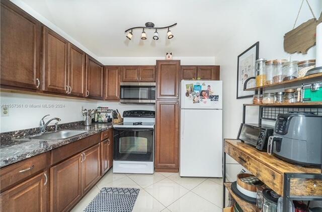 A kitchen features dark wood cabinets, stainless steel appliances, and a marble-patterned countertop — 185 Normandy # D, Delray Beach FL 33484, DELRAY BEACH, FL
