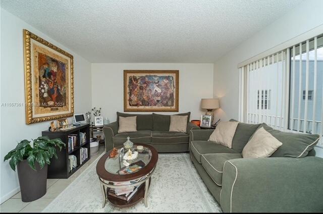 A living room features two green sofas, a glass-topped coffee table, and two framed paintings — 185 Normandy # D, Delray Beach FL 33484, DELRAY BEACH, FL